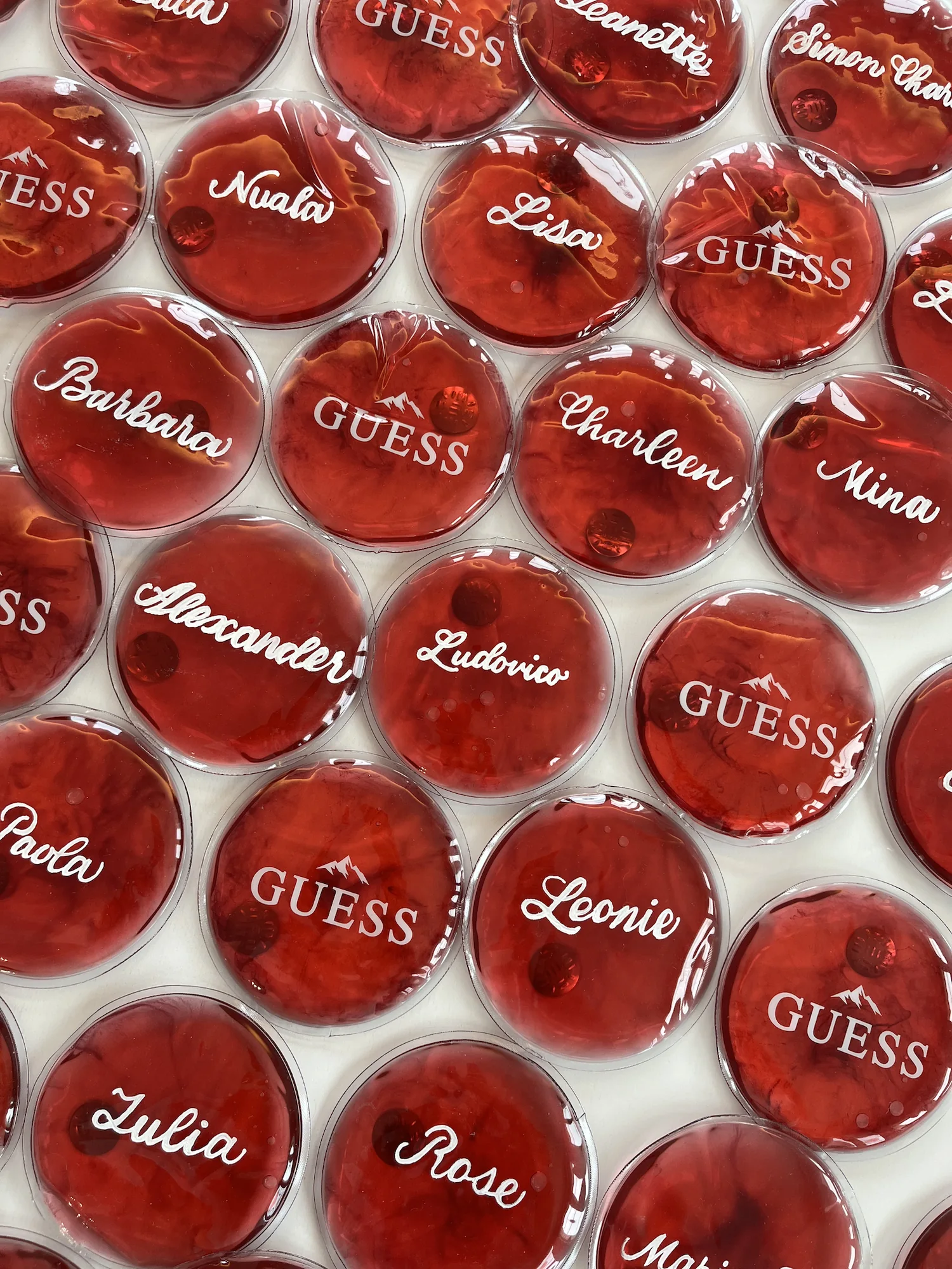 Red GUESS handwarmers personalised with names in white calligraphy