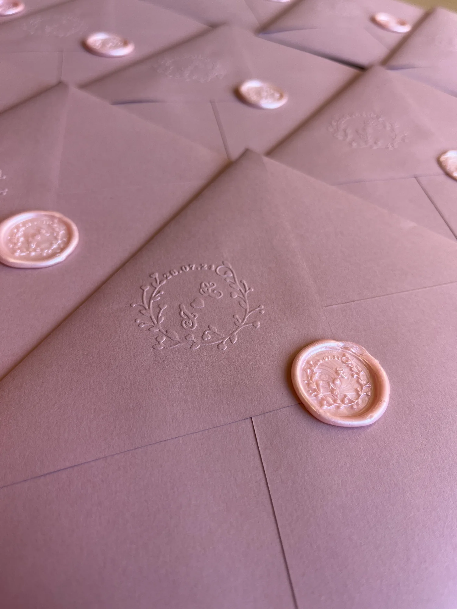 Blush envelopes embossed with a custom insignia and finished with matching wax seals