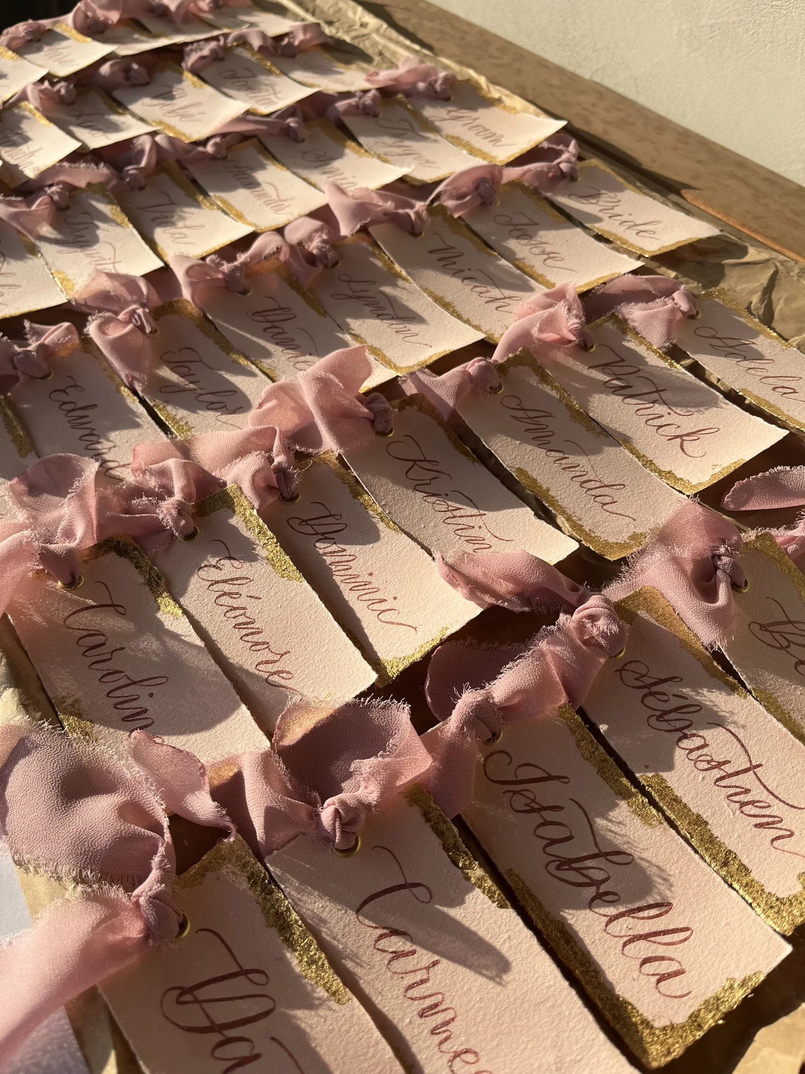 Rows of hand-lettered place cards tied with blush ribbon