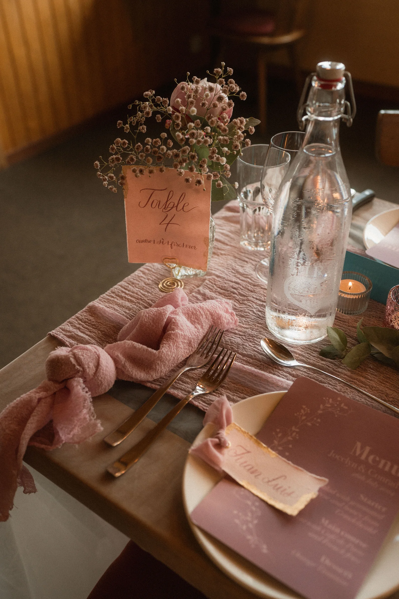 Hand-lettered table card among blush flowers and wedding tableware