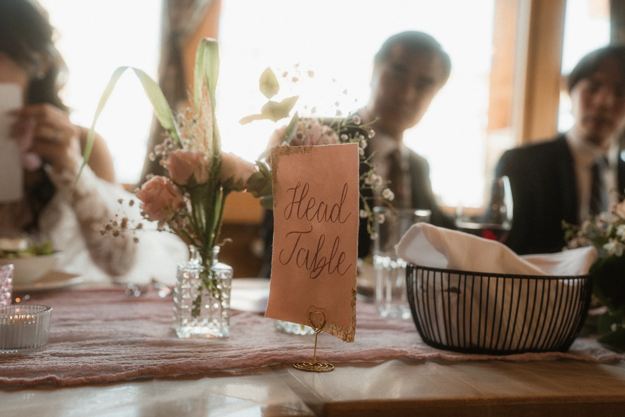 Hand-lettered head-table card among blush wedding flowers