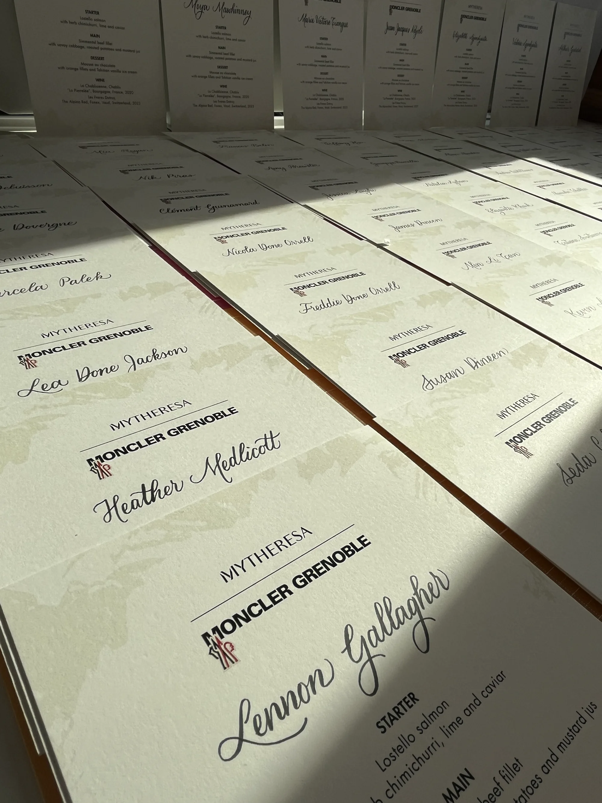 Rows of Moncler Grenoble and Mytheresa menus personalised with guest names