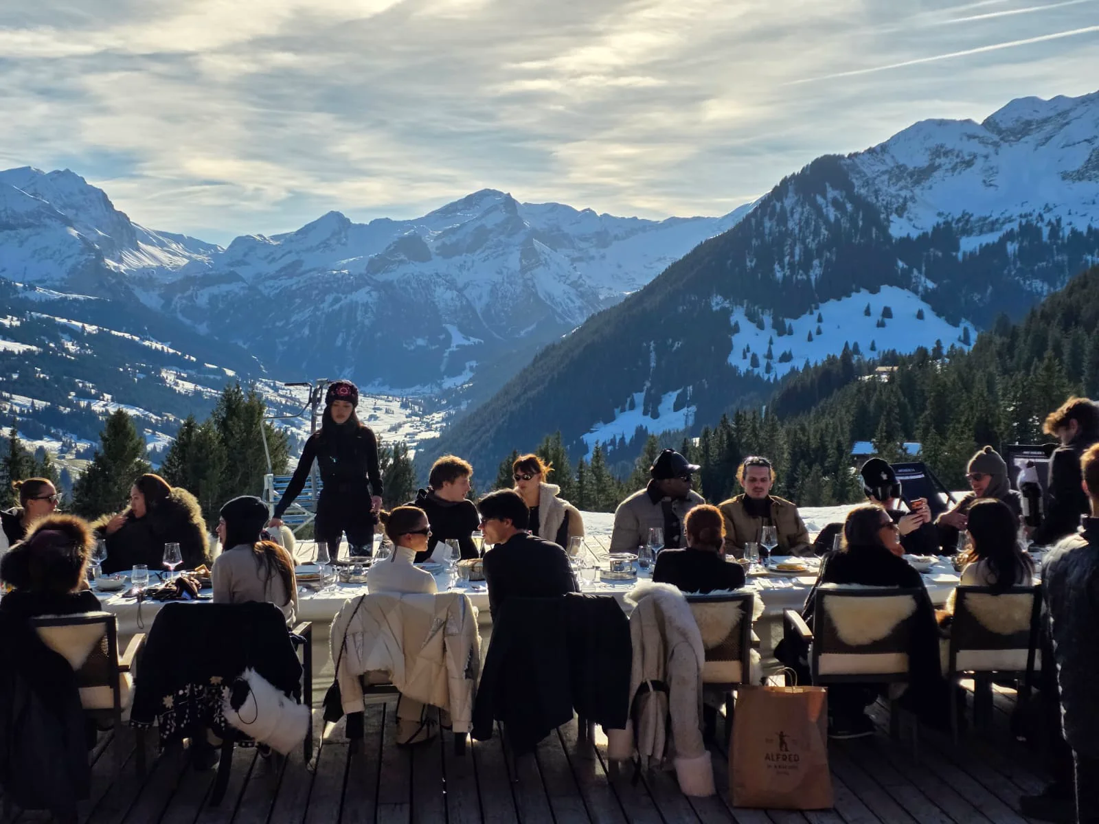 Guests seated at a fondue lunch on the Eggli terrace with a snowy mountain view